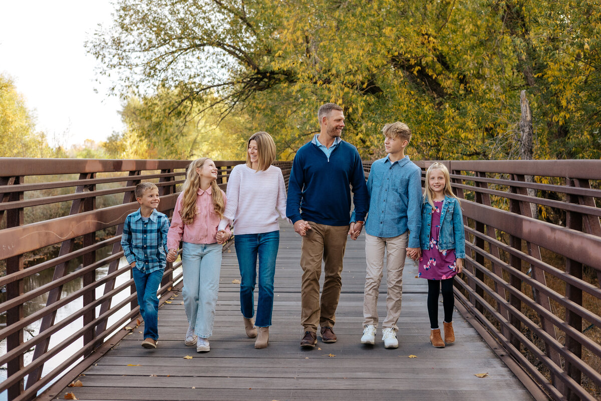 A family of 5 holds hands and walks towards the camera during their family session in Fort Collins, Colorado.