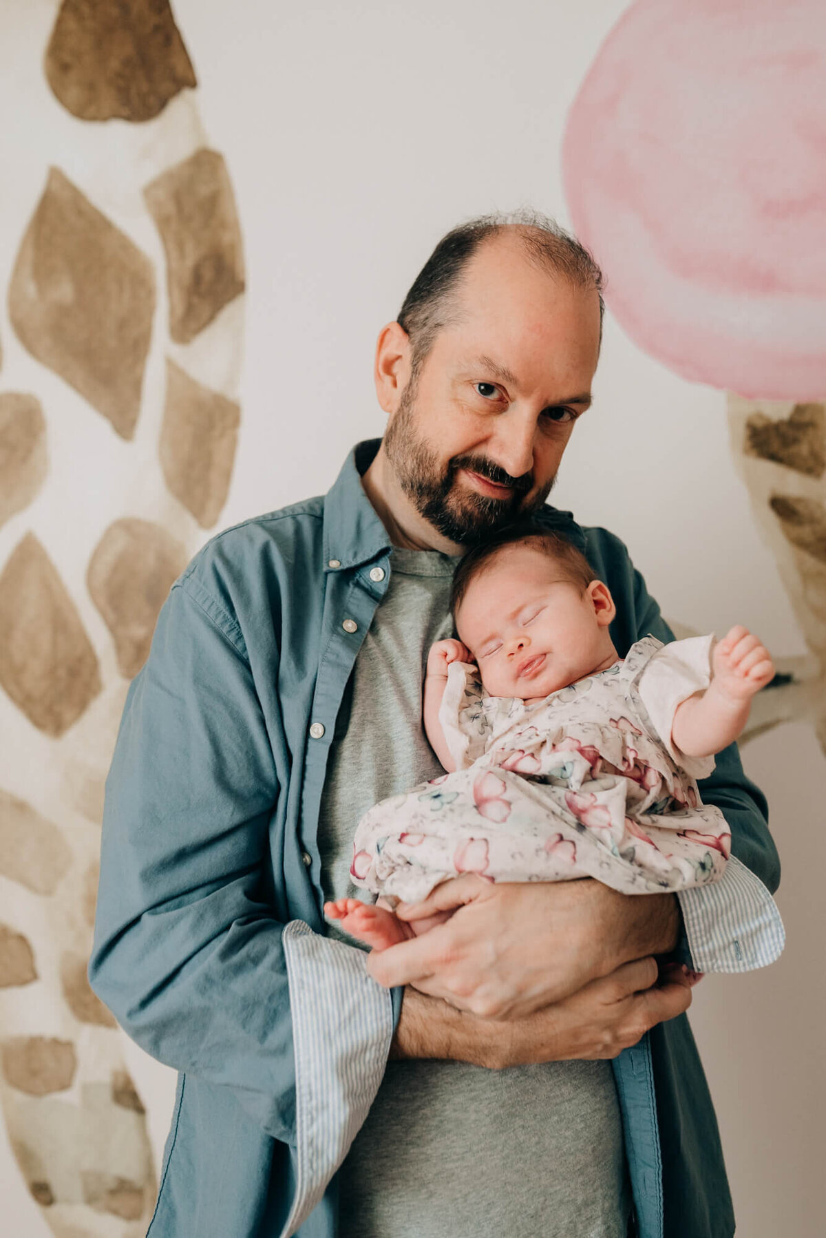 A father holds his sleeping daughter in her safari themed nursery