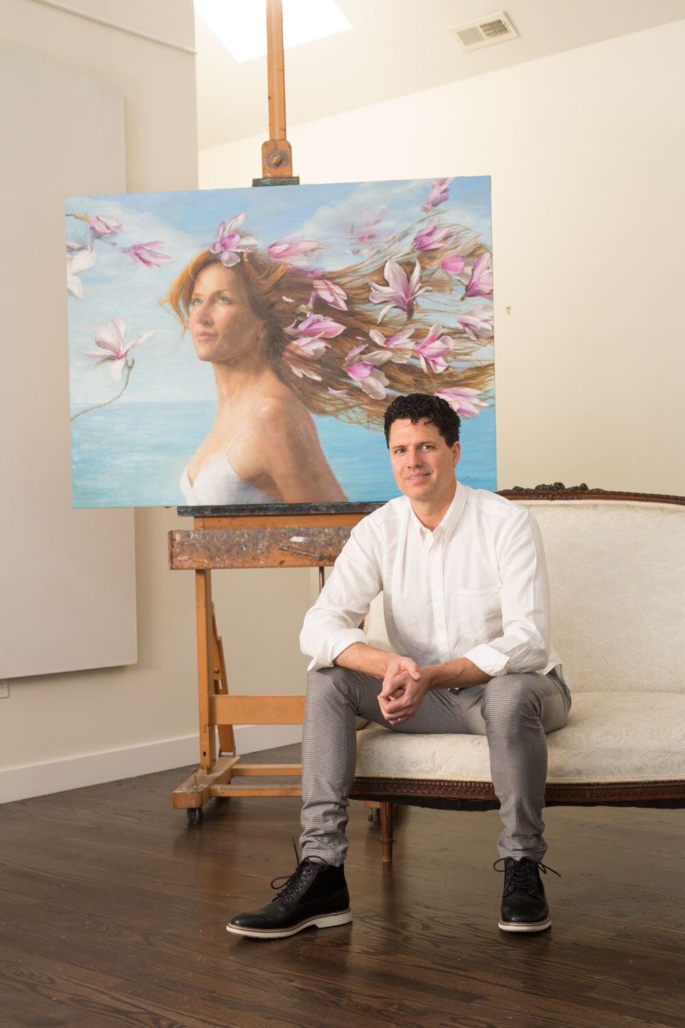 Man sitting in front of a floral portrait painting