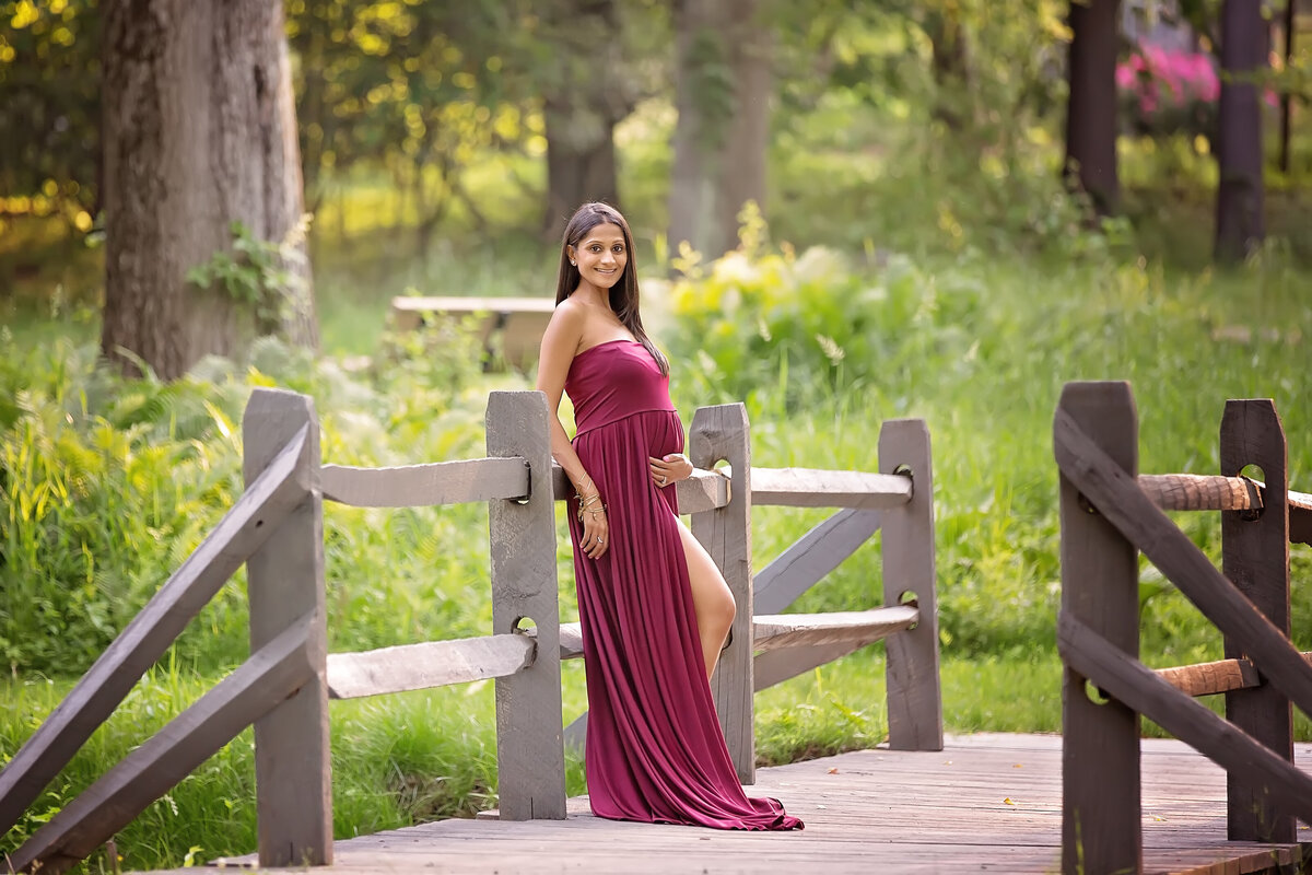 new jersey expecting mom wearing a red dress in a NJ park posing for her maternity session