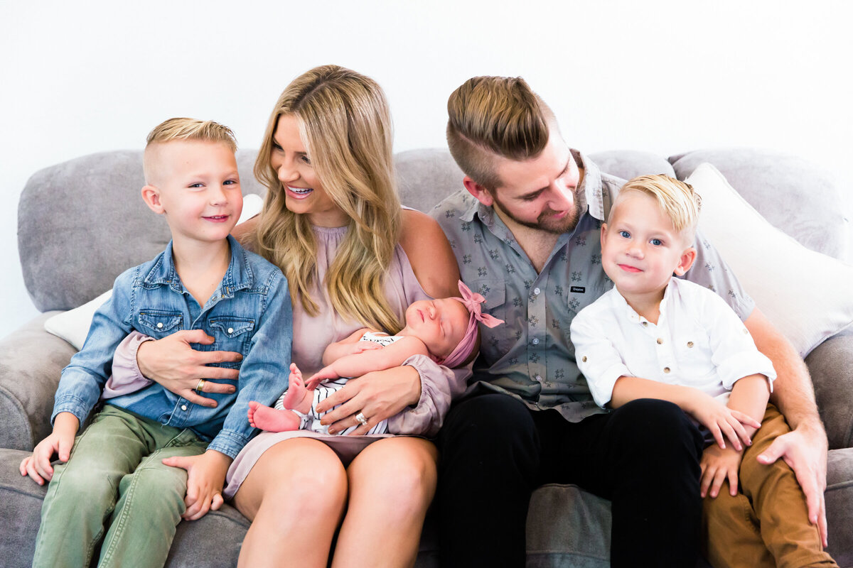 family smiling at each other and holding newborn baby