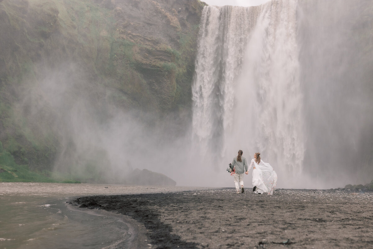 Bride and Groom running toward a waterfall in the Adirondacks. Photographyed by Nicole Weeks Photography.