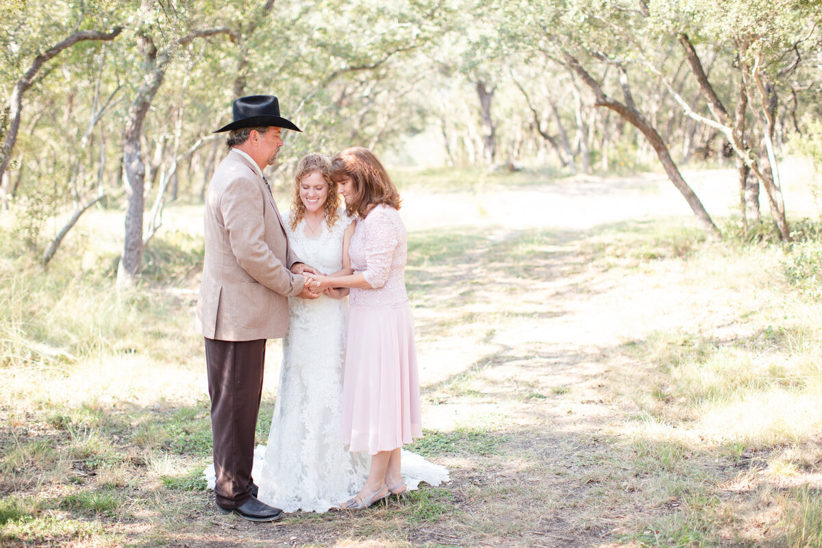 parents pray with their daughter at a hill country wedding venue by San Antonio wedding photographer Firefly Photography