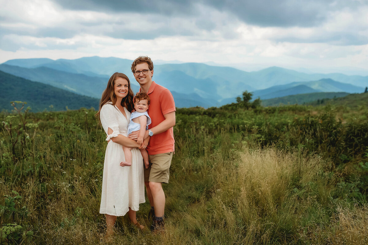 Parents embrace their baby during Family Pictures at Black Balsam on the Blue Ridge Parkway  in Asheville, NC.