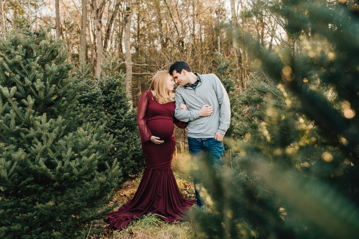 A pregnant mom and her husband in a Christmas Tree Farm in New Hartford, CT.