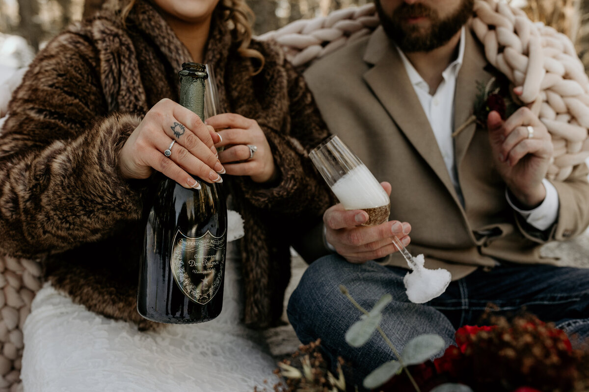 bride and groom drinking champagne in the snow