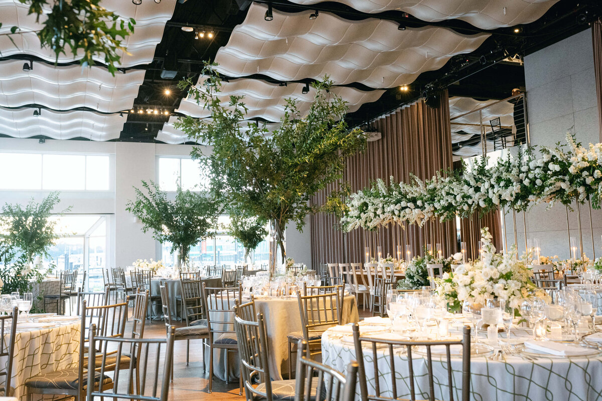 Wedding reception at Pier 59 Current with large trees, white and green linens, and all white flowers with candlelight