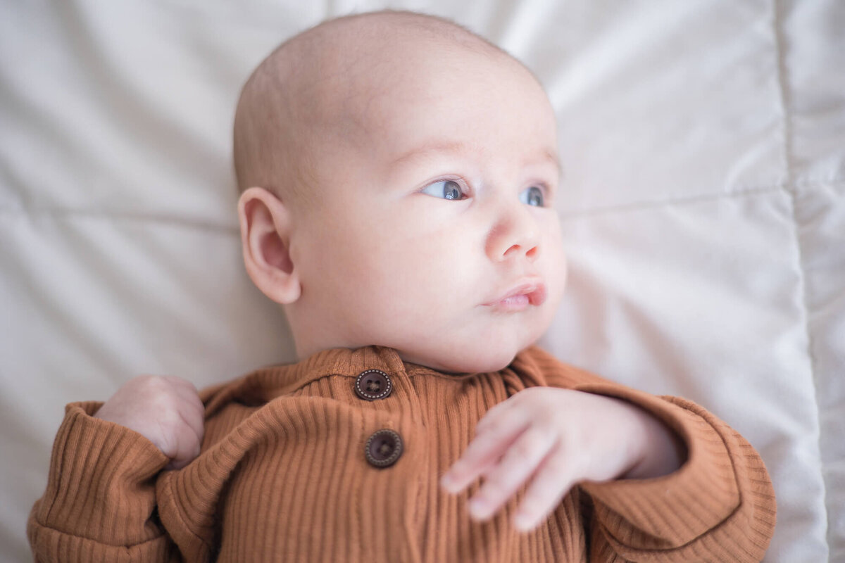 Infant baby boy looking at light while laying on a bed