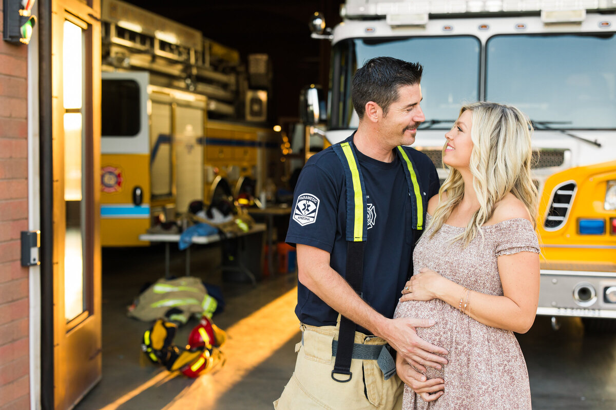 mom and dad to be posing for maternity photo at fire station