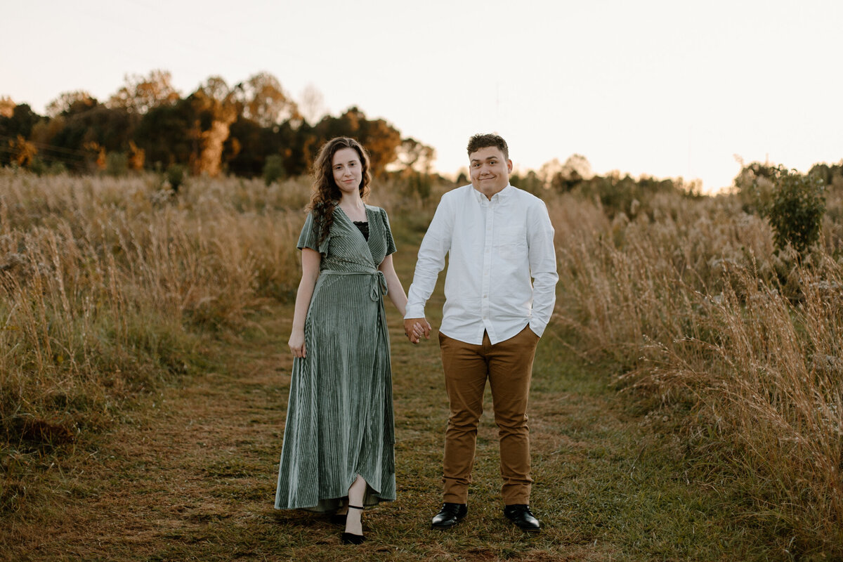 engaged couple walking in a field