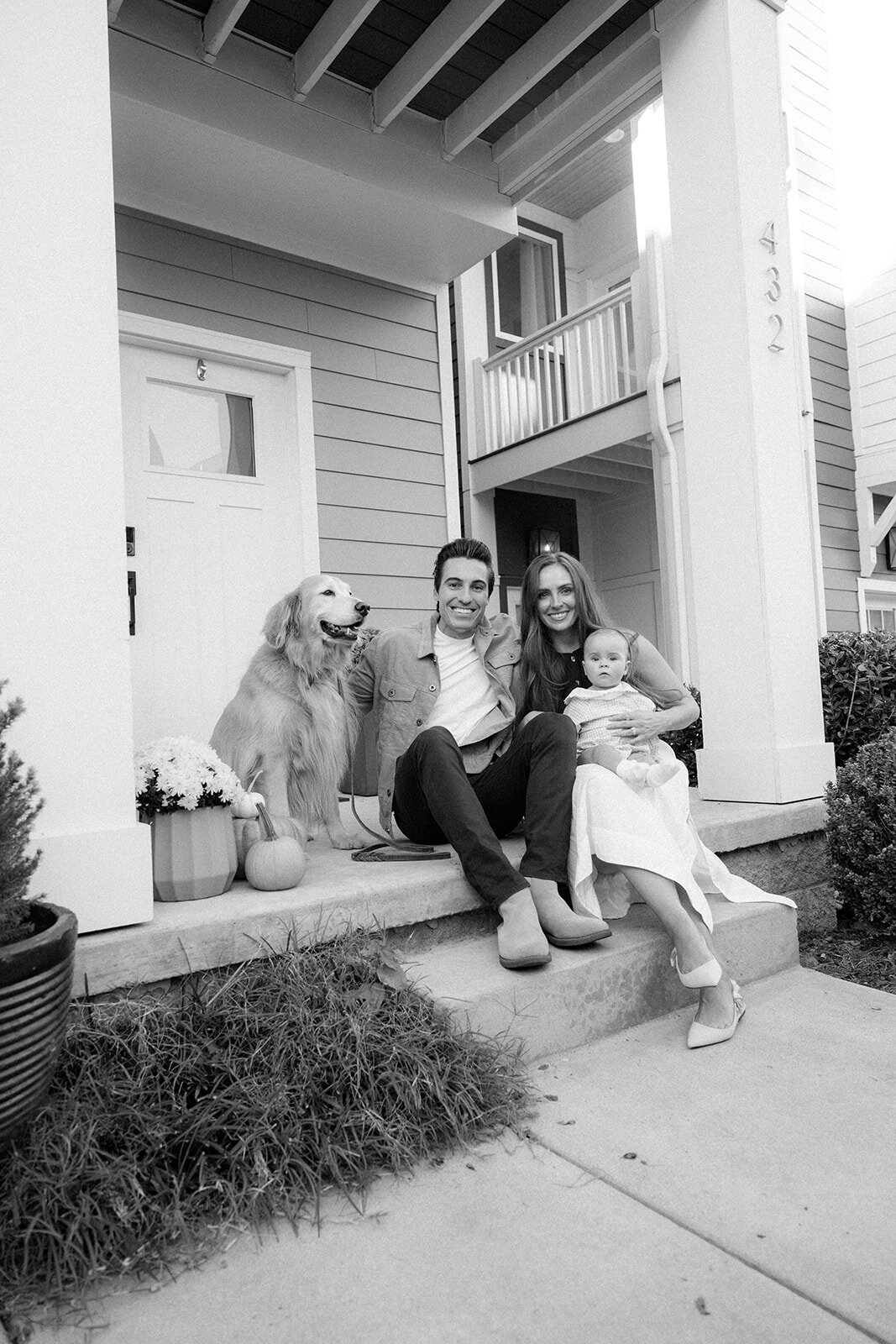 Family gathers with family dog on their front porch during fall family photos. 