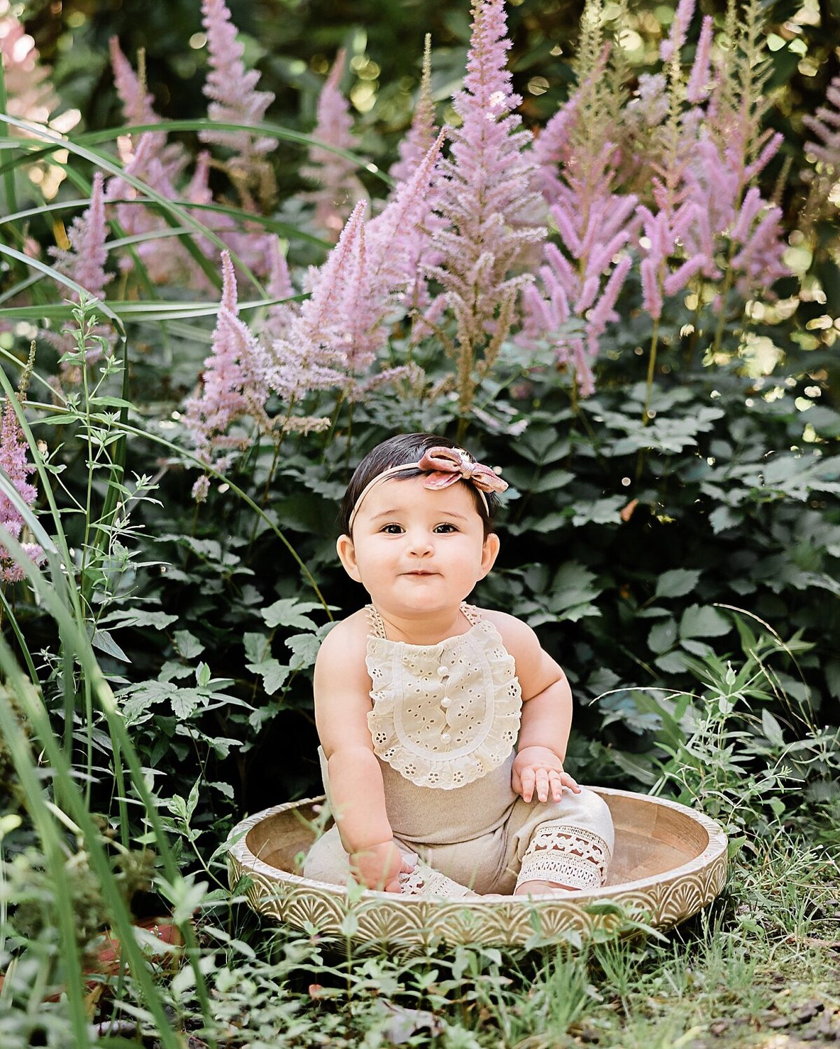 baby sitting in bowl with purple flowers with headband