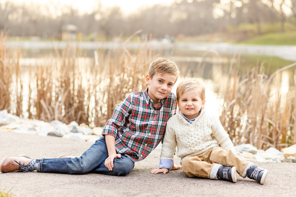 Brothers sitting in front of a pond smiling