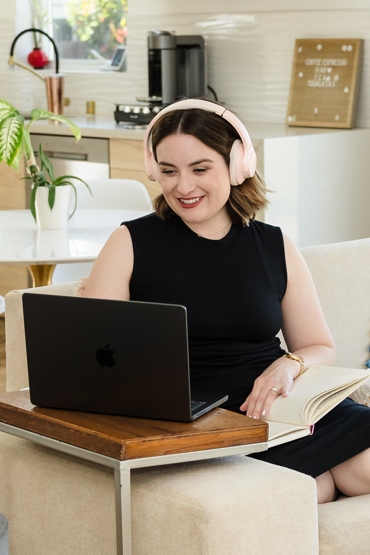 The content creator sits on the couch, working on her laptop, headphones on
