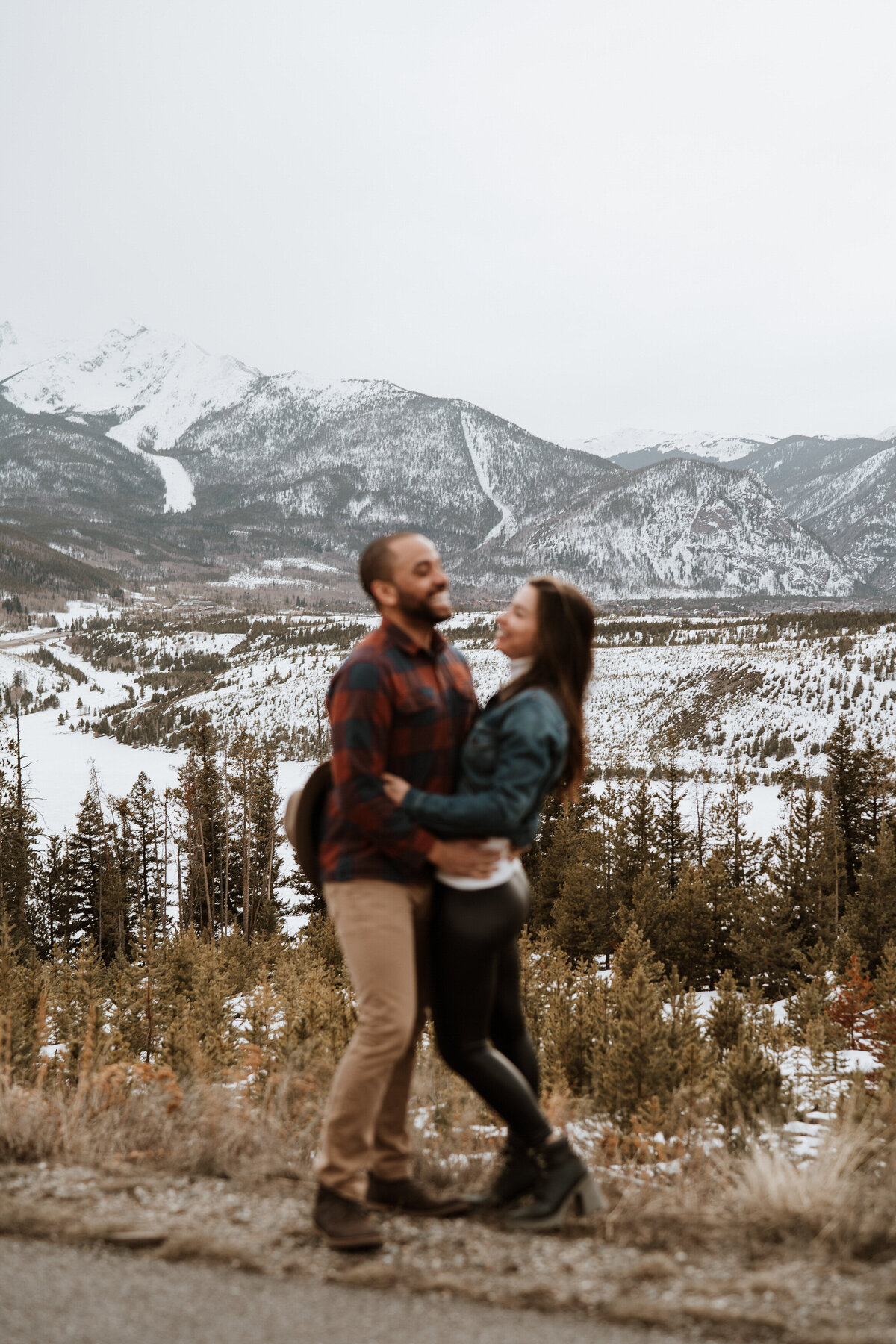 Couple snuggles in the snow with flannel and denim during Sapphire Point engagement shoot.