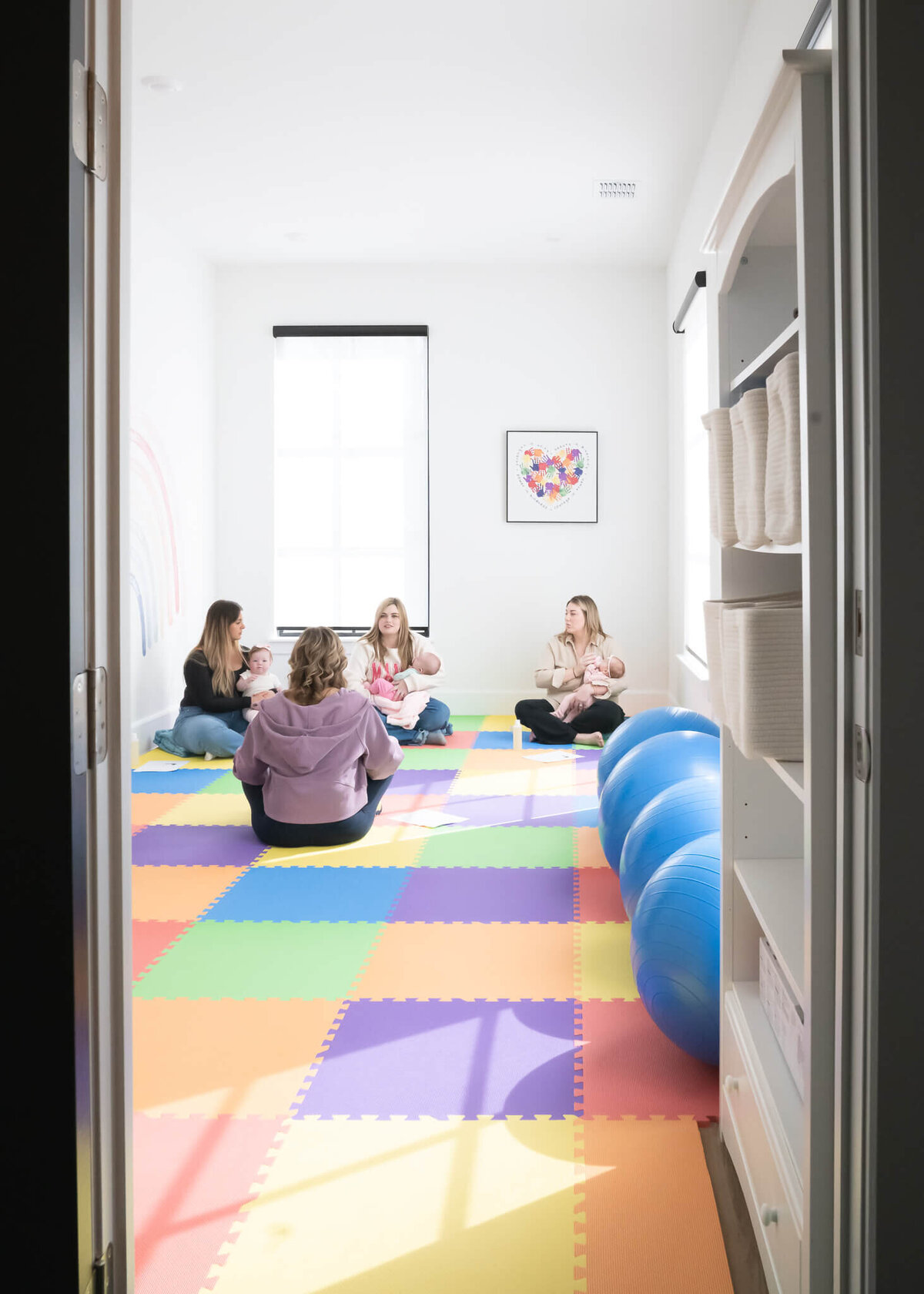 Therapist teaching infant massage and exercises to new moms during a class in her beautiful new space 