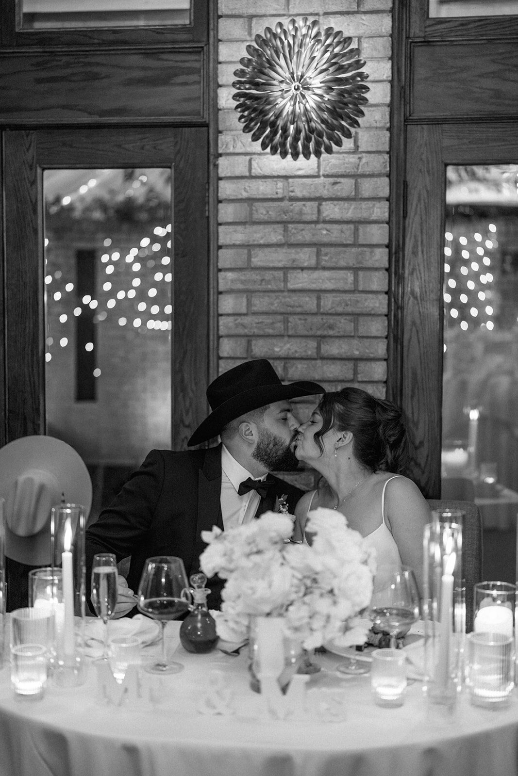 Bride and groom sharing a romantic kiss at their candlelit Café Cortina reception table.