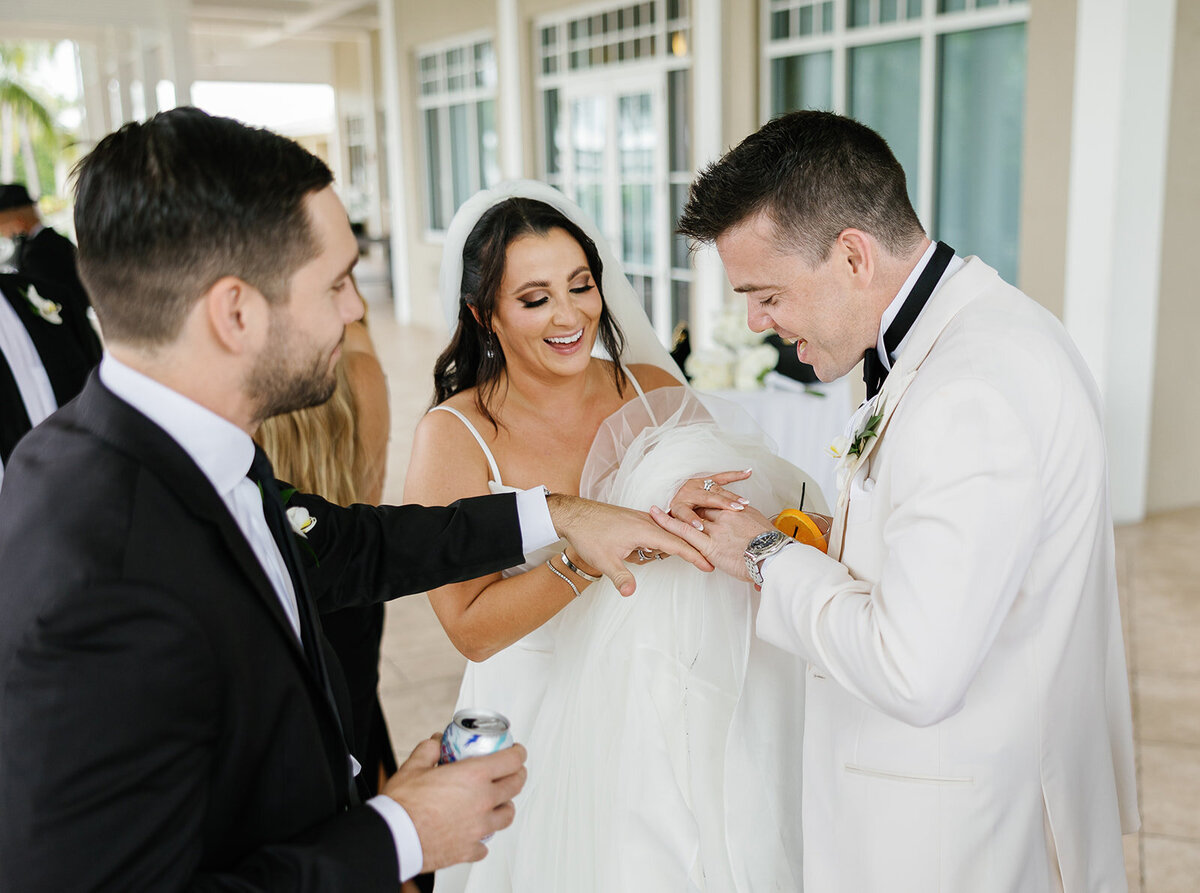 The bride and groom laughing together as they show off their rings during Ashley and Cameron's micro wedding at Ocean Reef in Key Largo, captured by Claudia Amalia Photography.