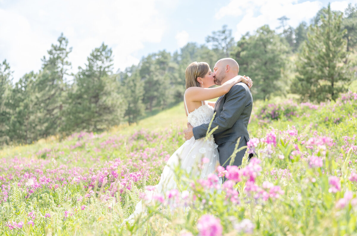 Groom and Bride sharing a romantic kiss in purple wildflower field on their wedding day in Colorado