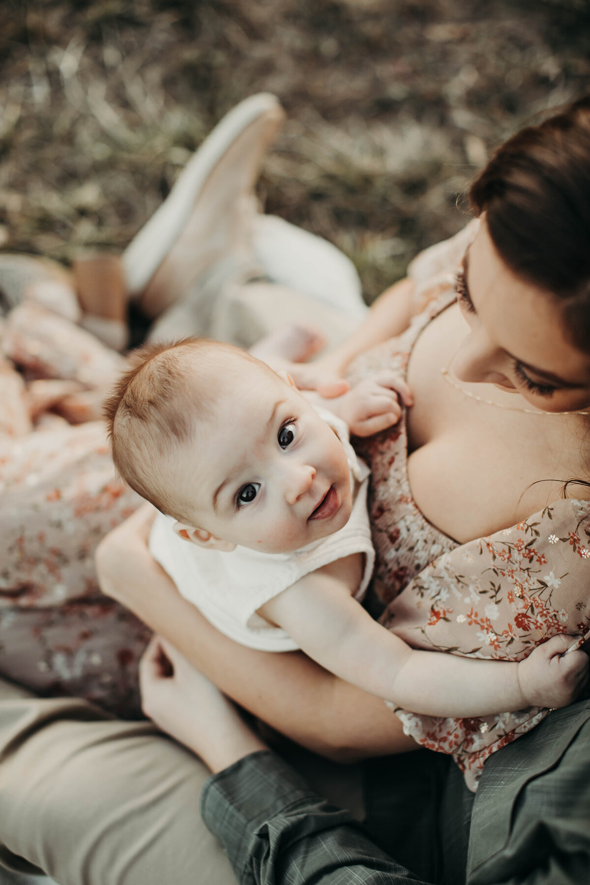 Photograph from above of baby smiling up at camera. 
