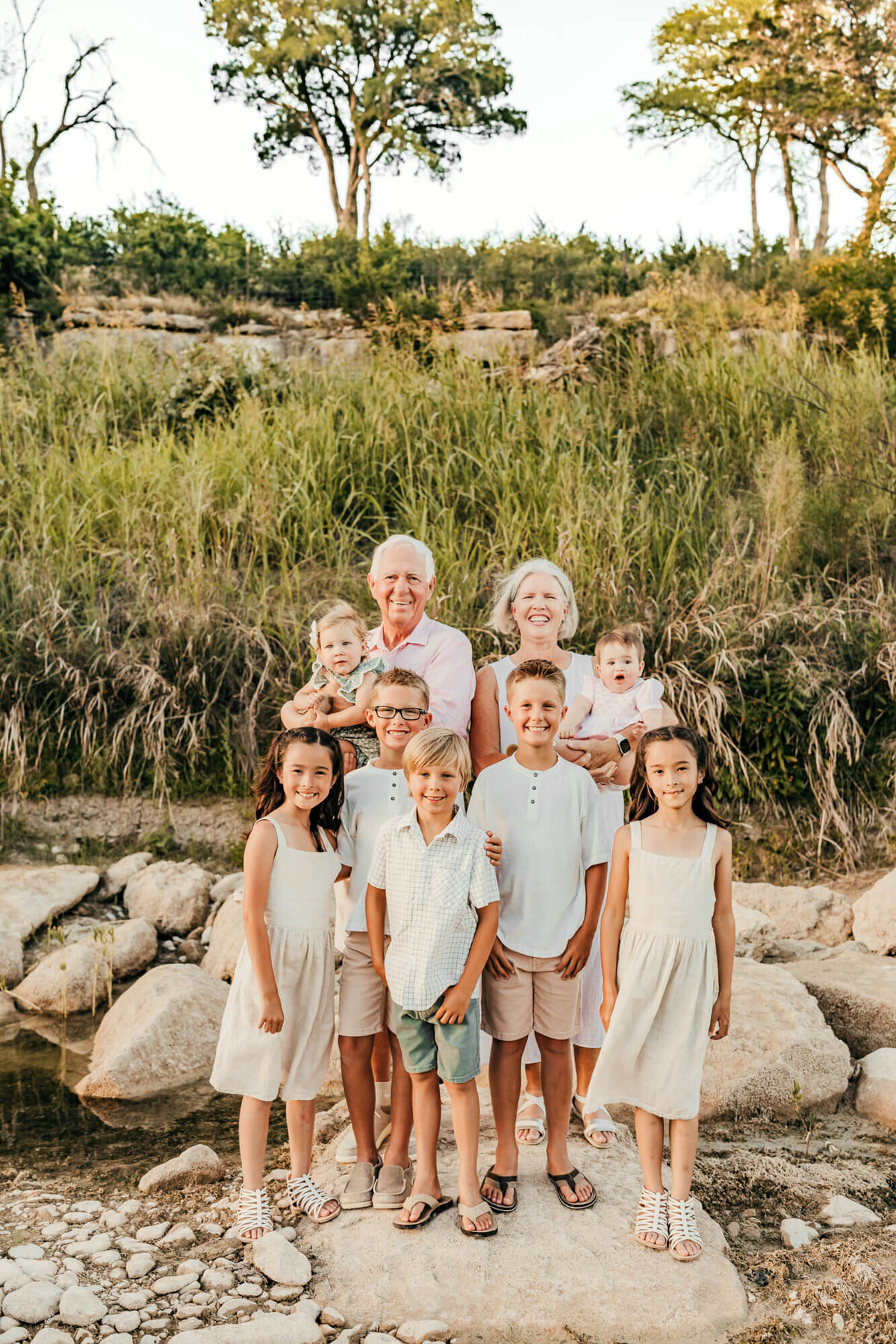 grandparents hold the baby grandkids while the others stand on rocks in the Hill Country.