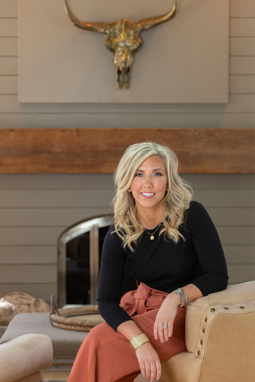 Woman smiling while seated in front of a fireplace