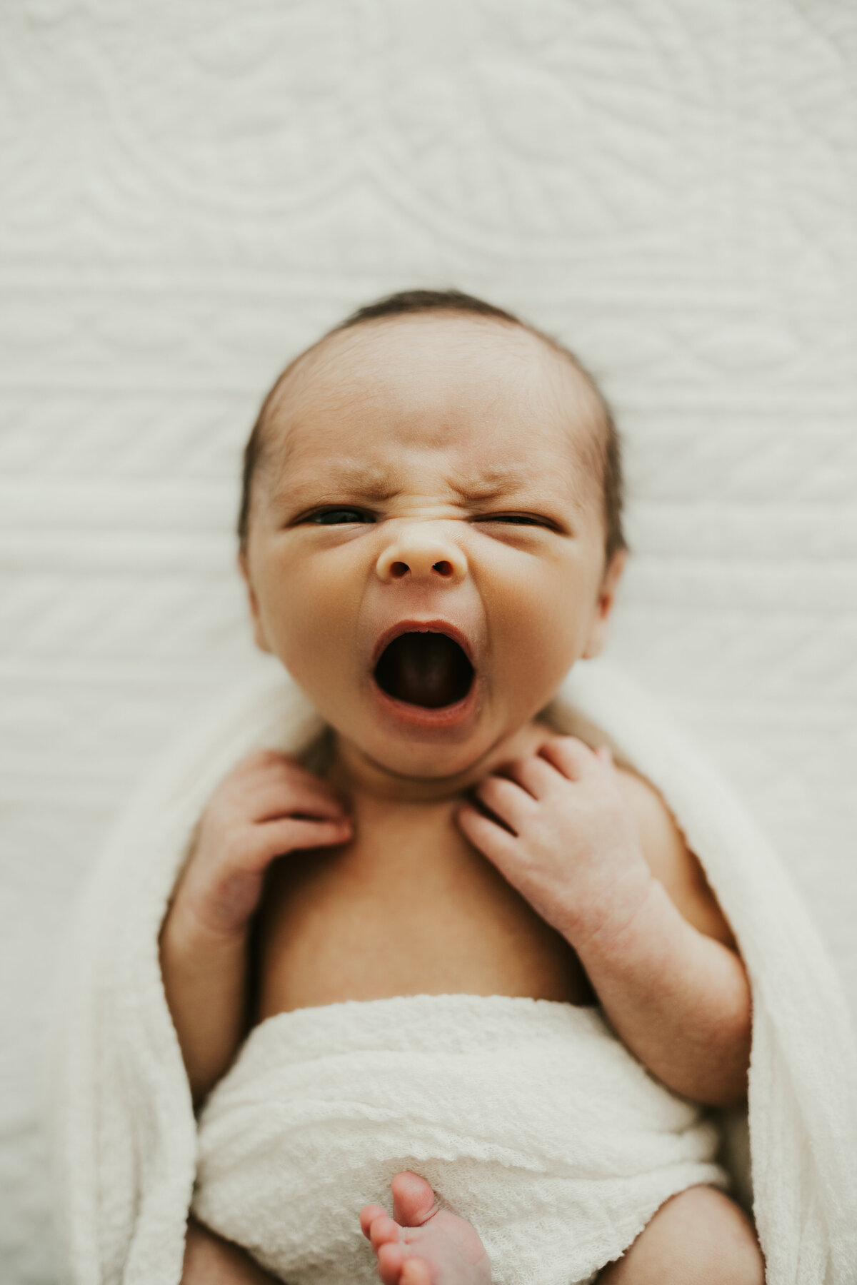Close-up of a newborn baby yawning during a candid in-home newborn photo session