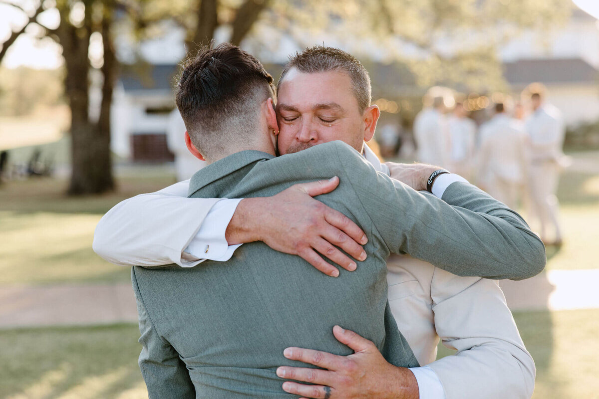 father hugging groom after wedding ceremony