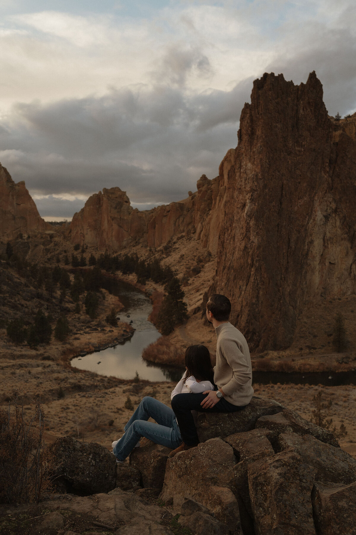 engaged couple sit on a rock and enjoy the views at Smith Rock State Park