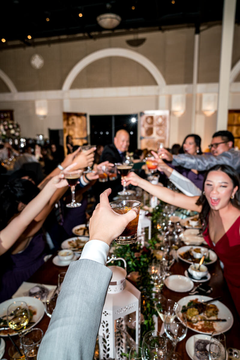 Wedding guests raise their glasses in a joyful toast during the reception at Casa Real, celebrating the bride and groom's special day with love and laughter.