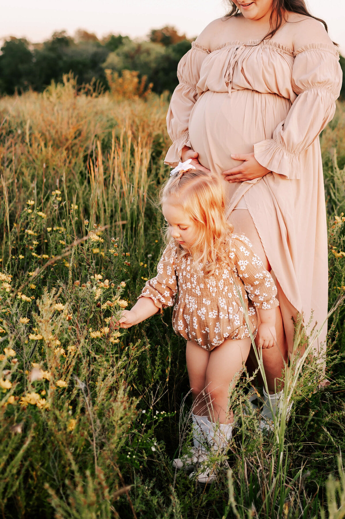 toddler picking flowers with pregnant mom watching in Joplin Missouri
