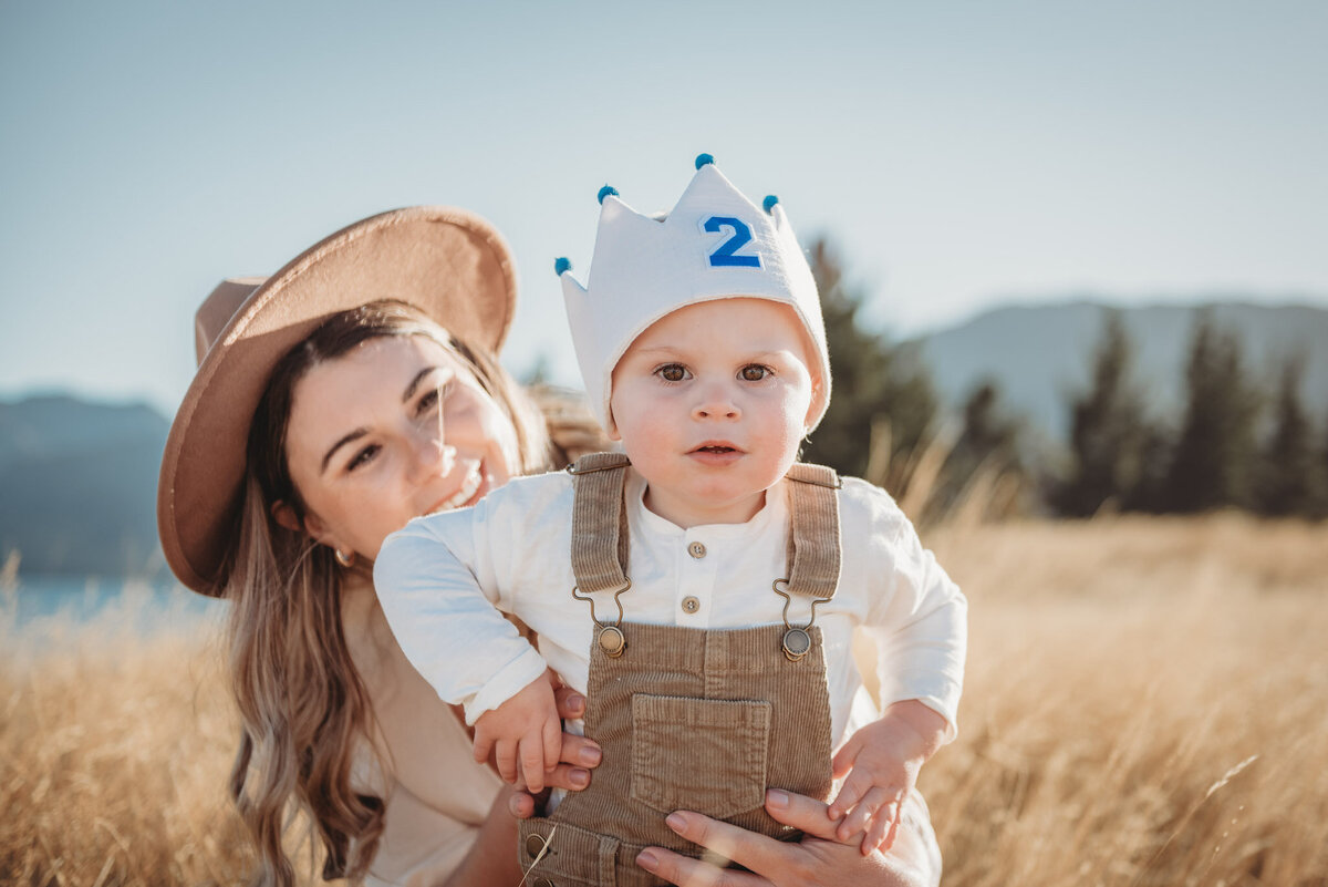 a boy standing in the field with his birthday crown held by his mum captured by Bie