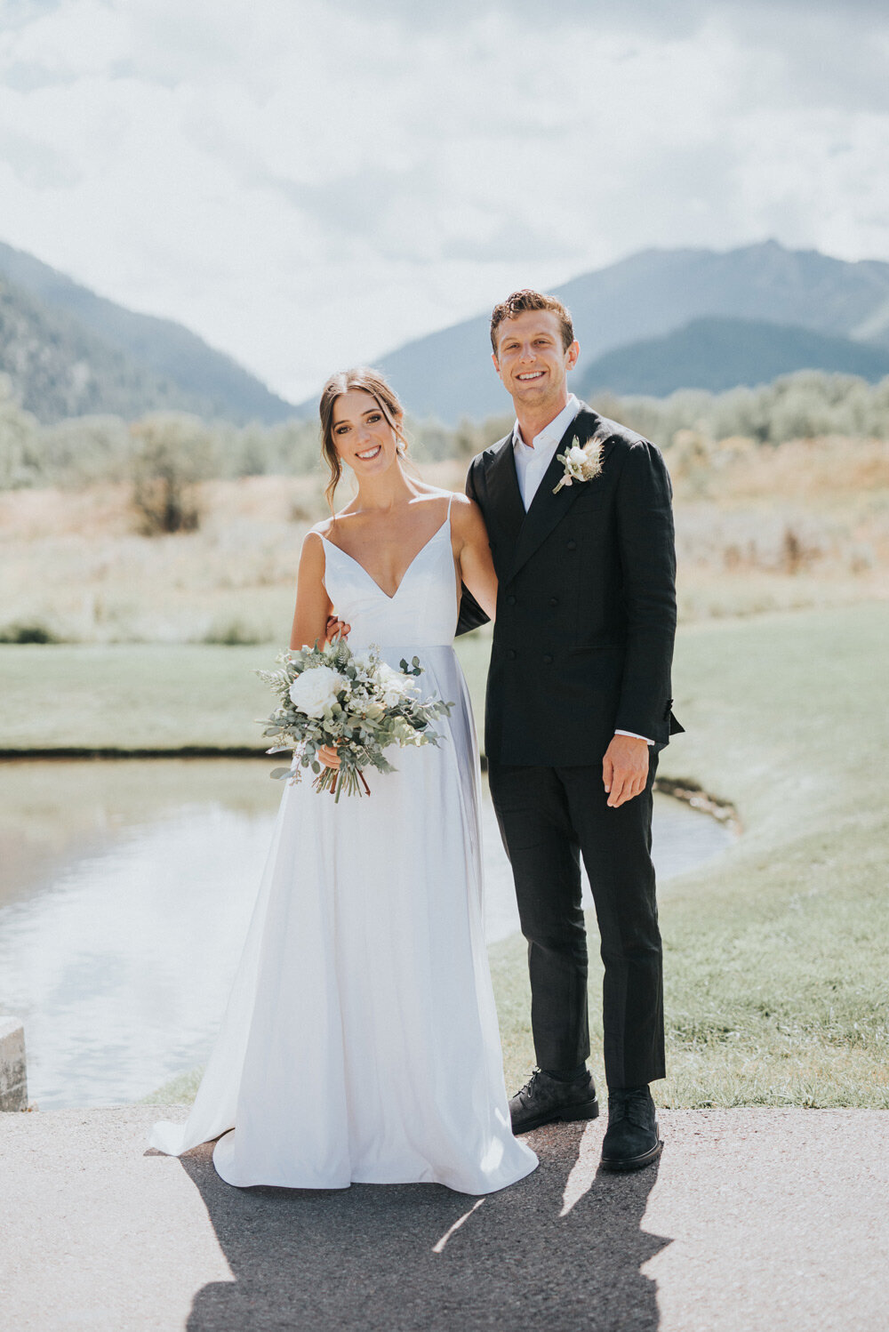 Smiling bride and groom wedding portrait with mountains in the background