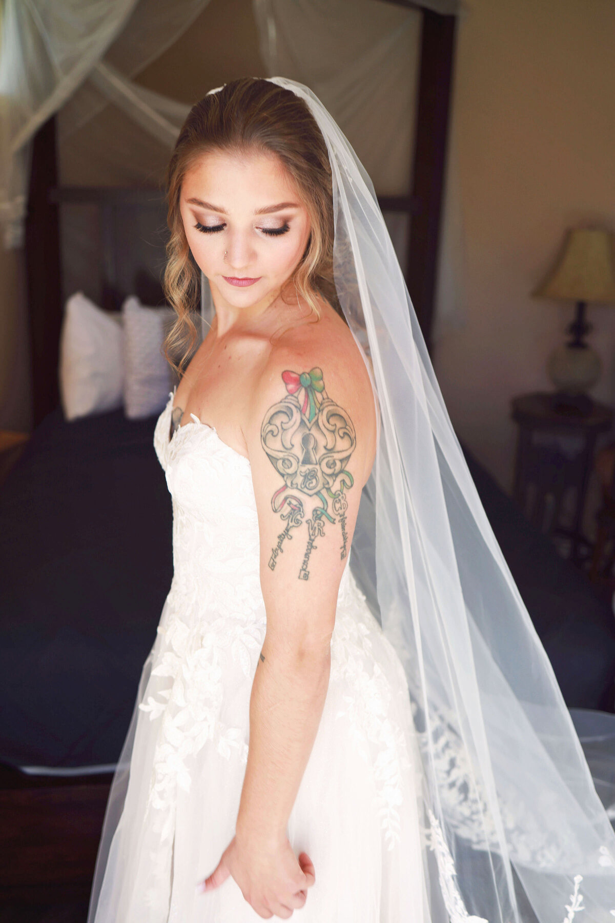 A young bride looks down across her left shoulder, highlighting her beautiful tattoo on her shoulder.