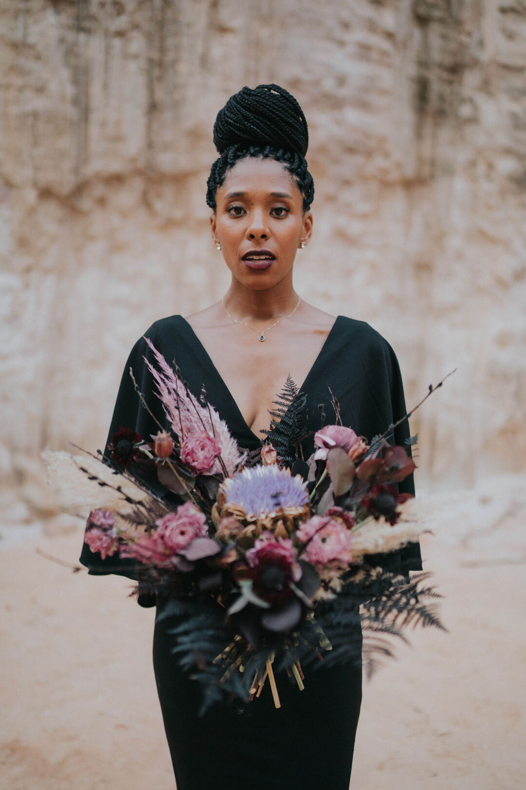 Black woman in a black dress holding a pink bouquet