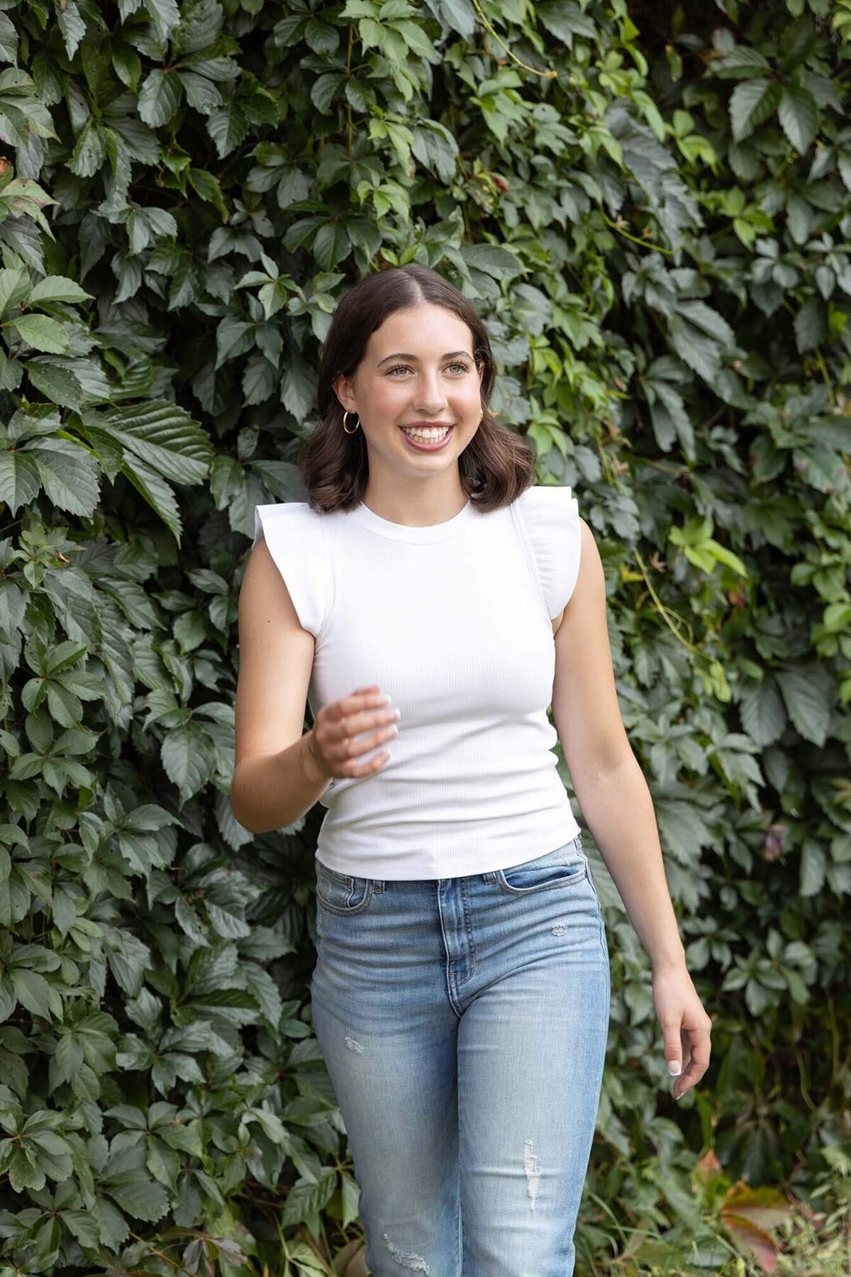 happy-senior-girl-on-green-vine-wall