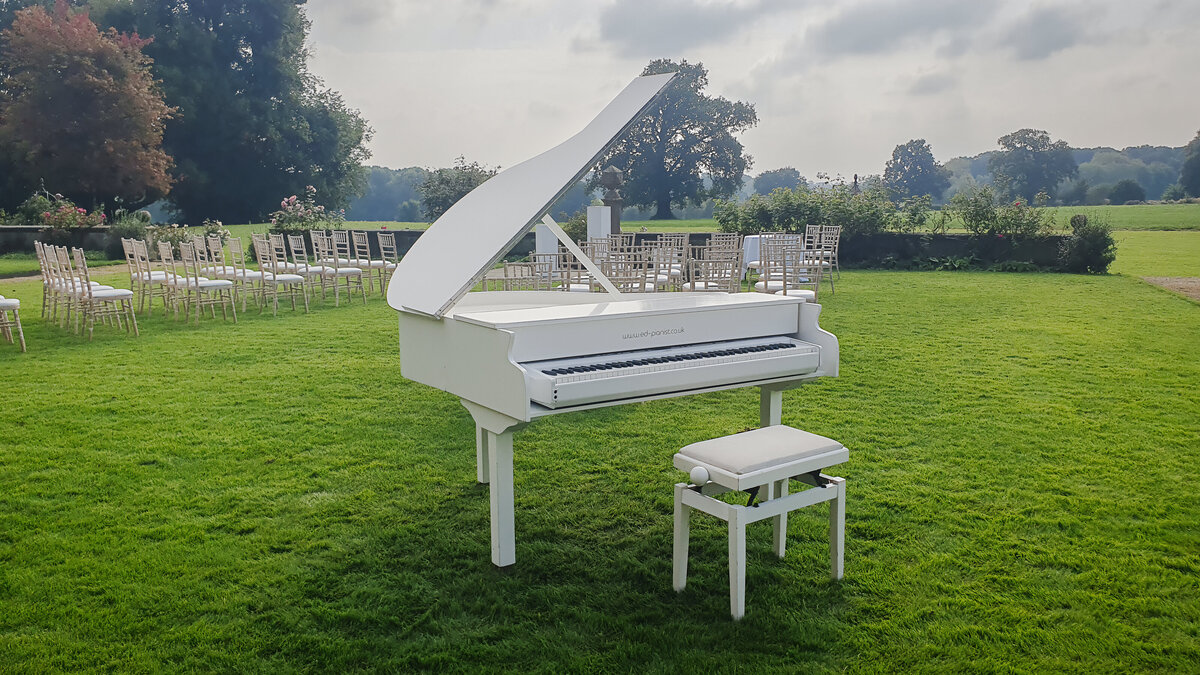 white baby grand piano outside wedding summer ceremony