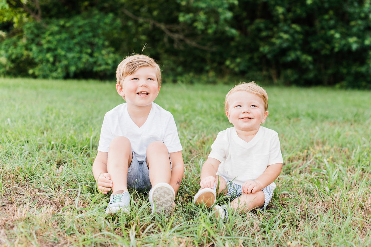 Brothers sit in the fields of Horseshoe Nature Preserve in Wake Forest NC during their family photo session. Photographed by Raleigh NC family photographer A.J. Dunlap Photography.