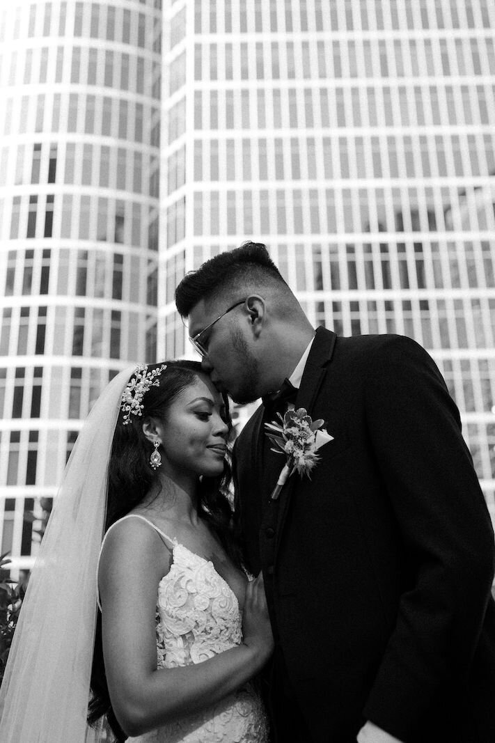 groom kissing bride on head