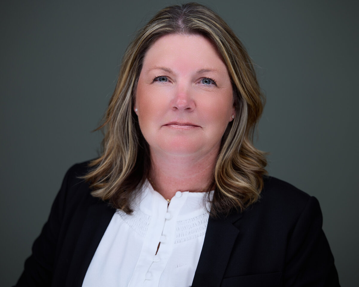 Headshot in CT of woman with shoulder-length hair wearing dark blazer and white blouse, smiling by Rob Faber Photography.