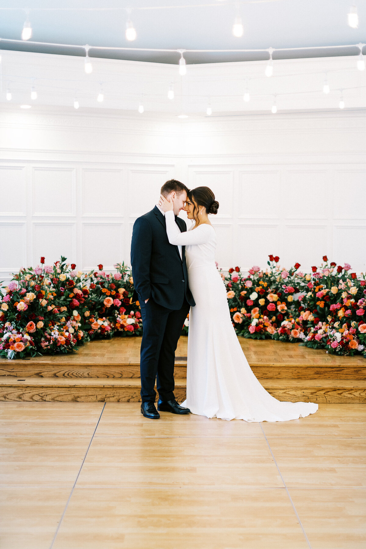 Bride and Groom touching foreheads surrounded with beautiful roses.