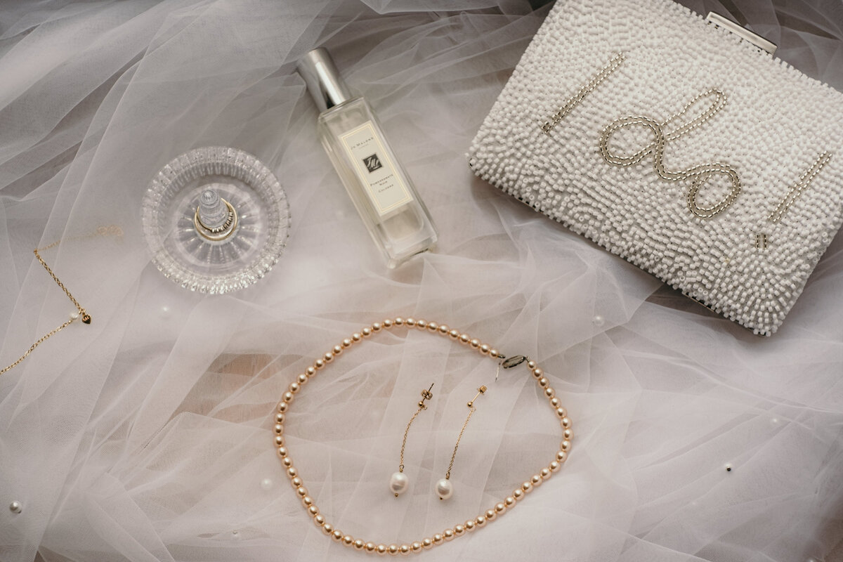 Der Schmuck der Braut liegt mit ihrem Schleier bereit zusammen mit Parfüm und Handtasche.