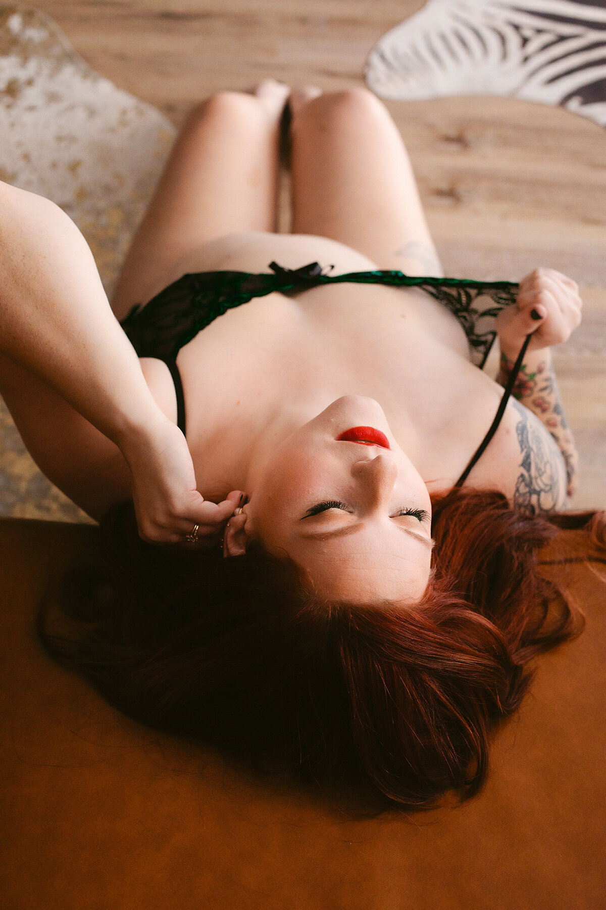 A woman seductively pulls at her green lingerie at a Bentonville Boudoir studio.