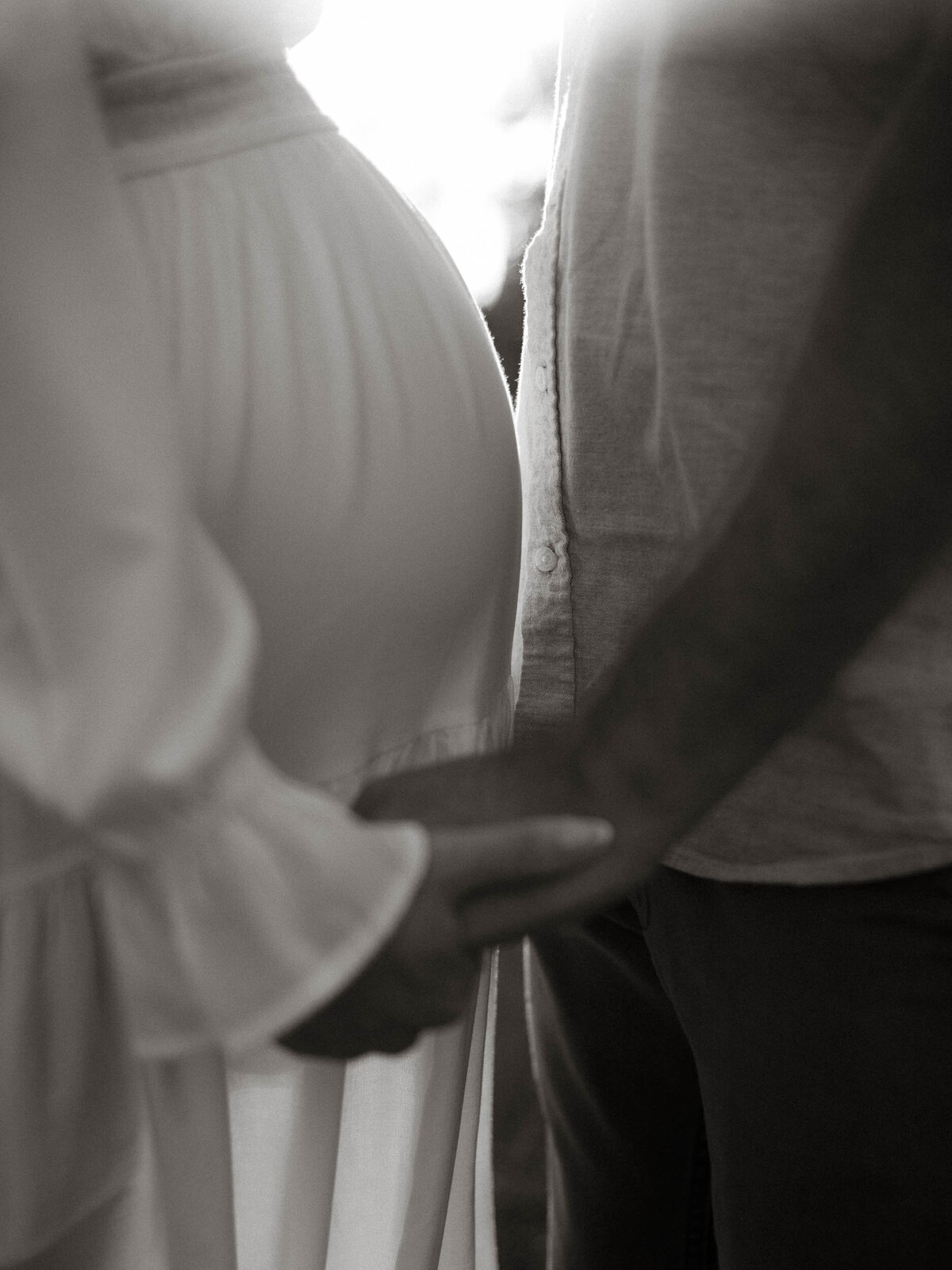 A profile image of mom and dad holding hands while sunlight comes through between them, in black and white.