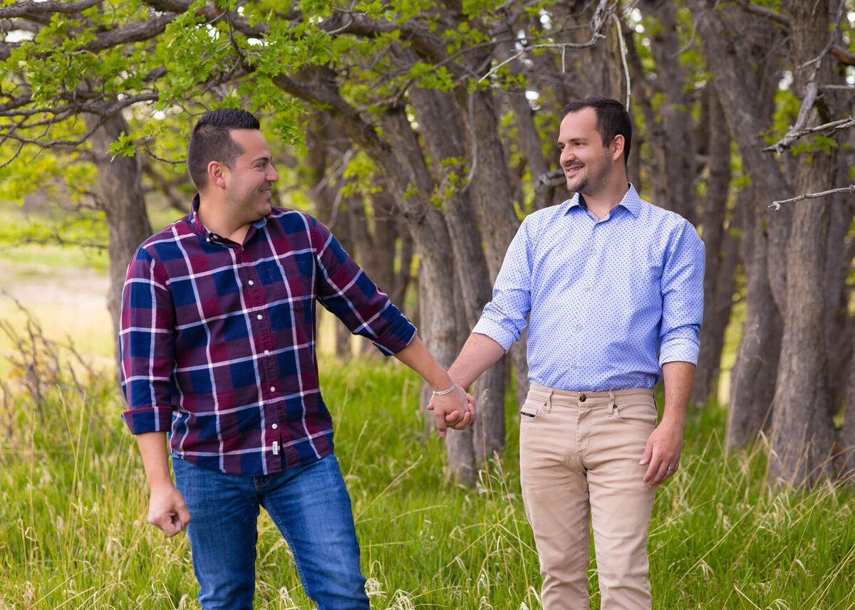 husband's holding hands looking at each other in a field