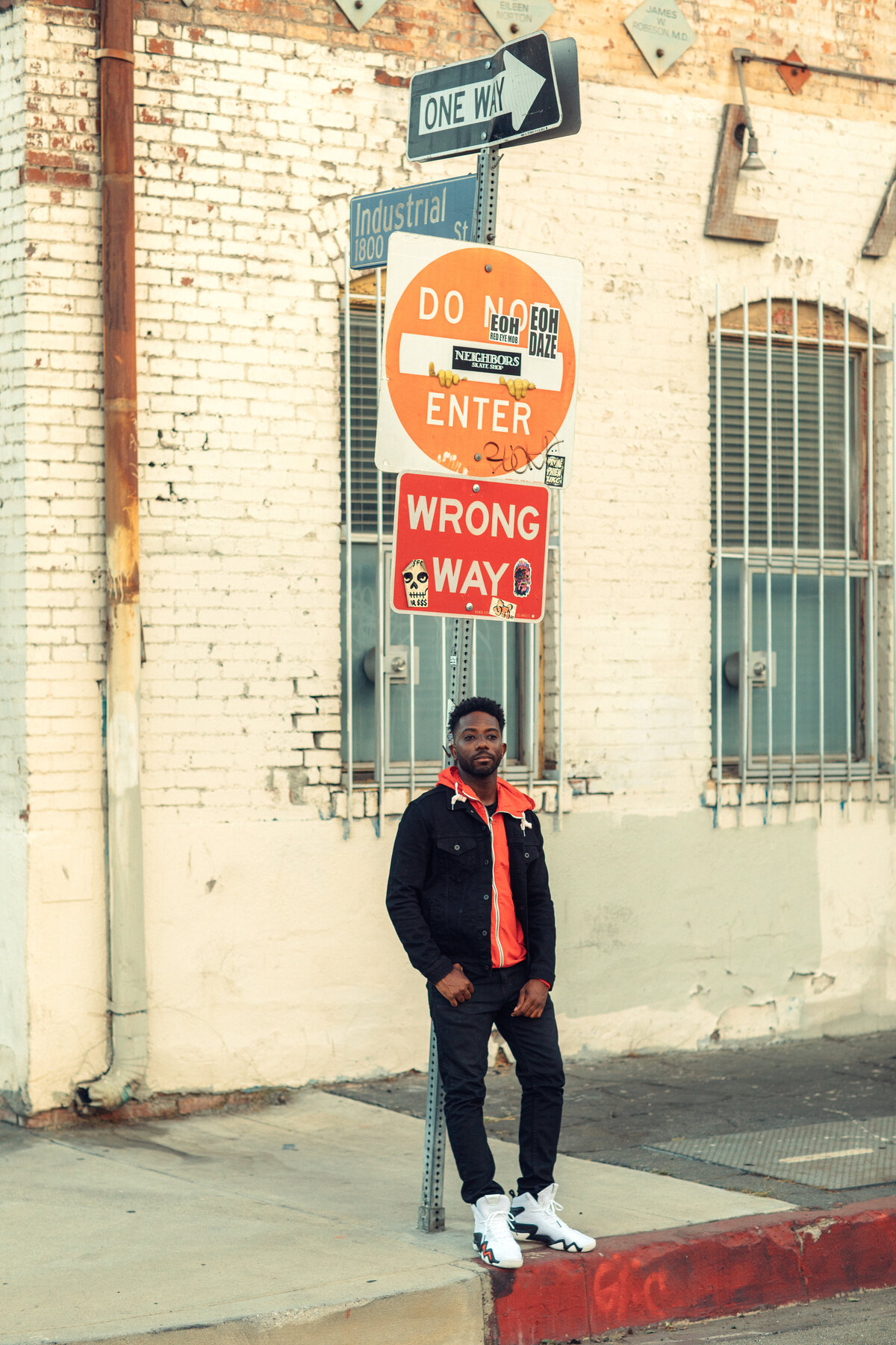 Portrait Photo Of Young Black Man Leaning Against a Road Signage Los Angeles