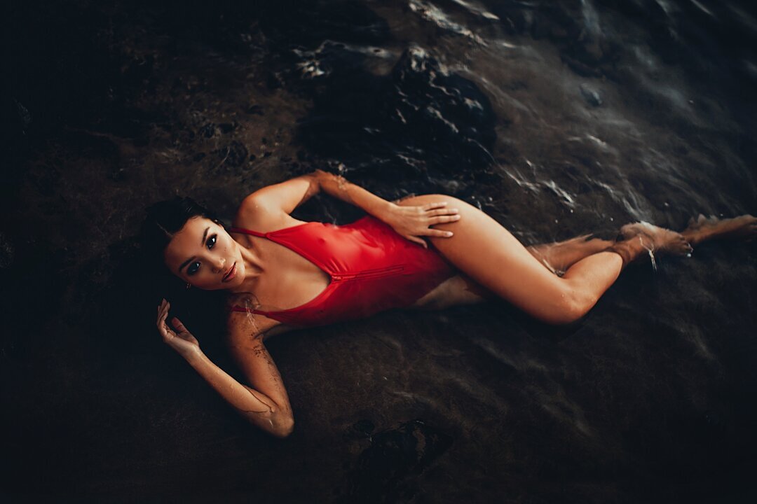 Ocean boudoir photo of a woman in a red bathing suit