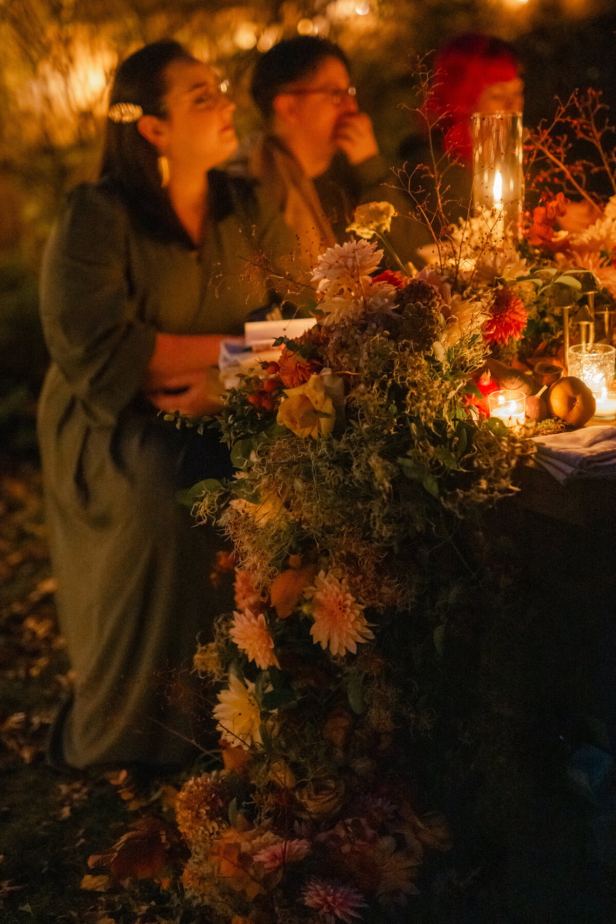 Rachel sitting surrounded by friends at candlelit table