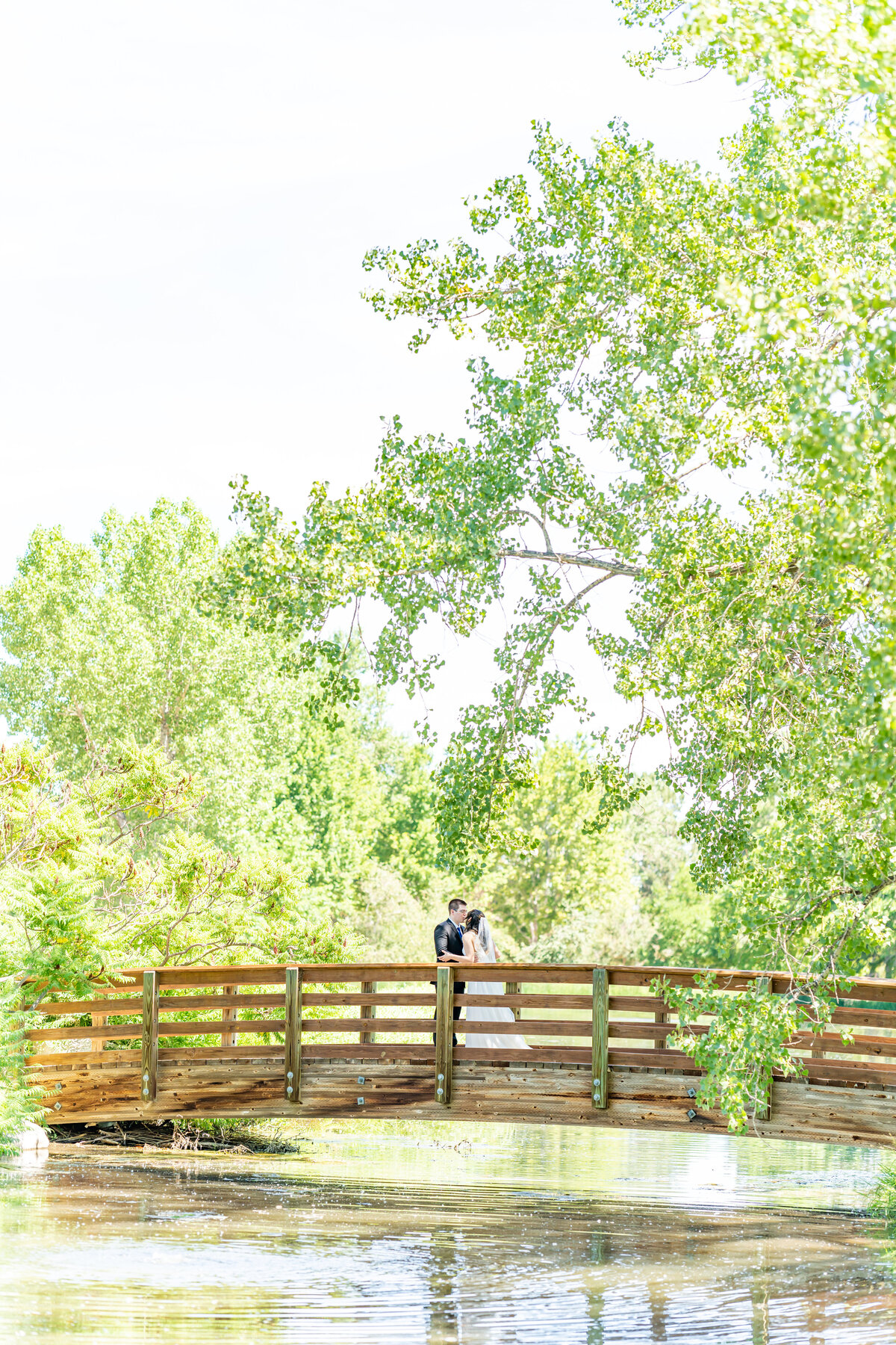 Bride and groom kissing on a bridge at Hudson Gardens and Event Center