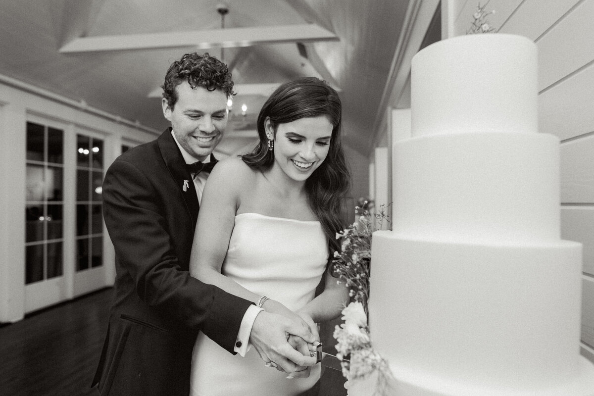 bride and groom cutting wedding cake at reception matties austin black and white